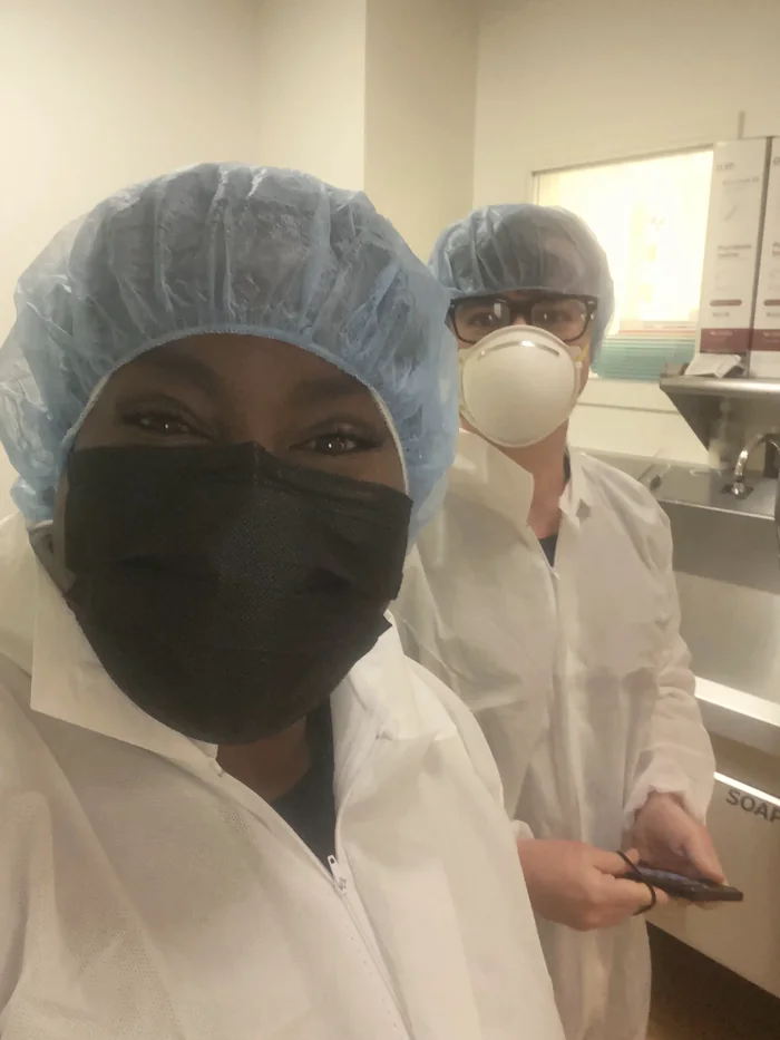 Morgan in surgical cap, mask, and gown, ready to accompany a client into the operating room for a cesarean birth.